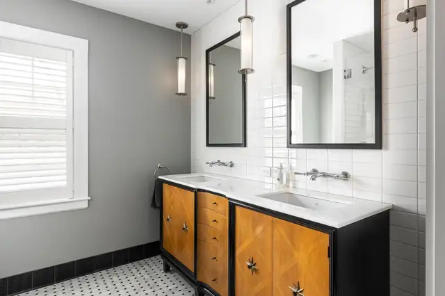 Bathroom by Forward with a black and walnut double vanity, white subway tile and black framed mirrors