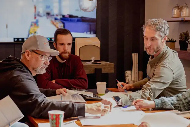 Forward designers and carpenters reviewing plans together at a table