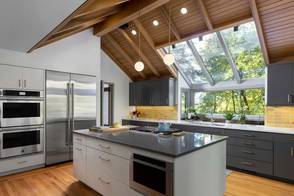 Kitchen remodeling Ann Arbor: vaulted wood plank ceiling, wall of windows, gray island and stainless double wall ovens